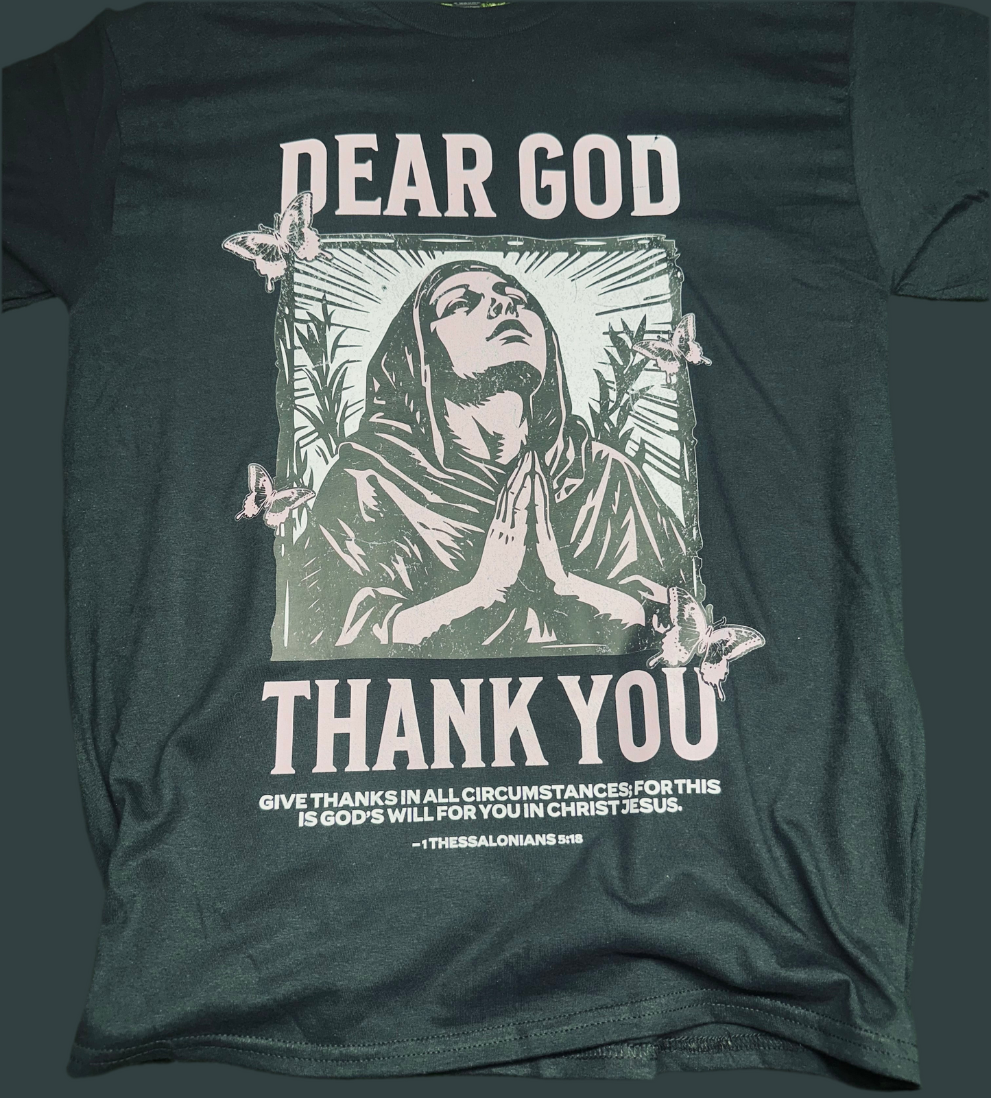 Dark green t-shirt with a graphic of a praying figure and text on the back.